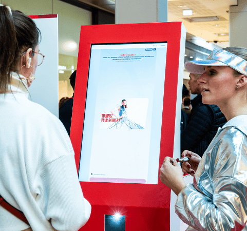 Borne interactive avec QR code pour animation commerciale et collecte de leads Utilisateur scannant un QR code sur une borne interactive pour participer à un jeu en magasin
