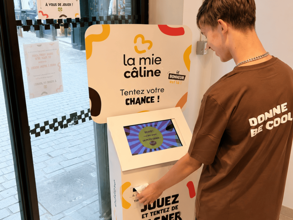 borne-plv-interactive-point-de-vente-la-mie-caline.jpg Client participant à un jeu Jackpot sur une borne interactive La Mie Câline.
